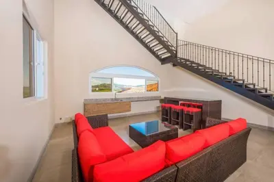 a living room with a red couch and a staircase at Pen16 Luxury 3bd Condo in Excl Resort Complex in Tamarindo