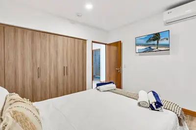 a bedroom with a white bed with a wooden cabinet at Pen16 Luxury 3bd Condo in Excl Resort Complex in Tamarindo