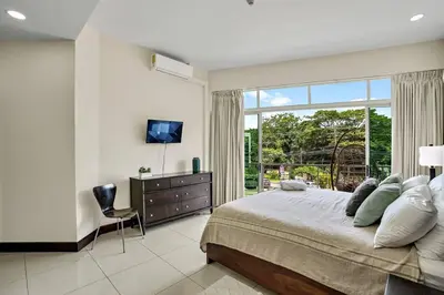 a bedroom with a bed and a large window at PP201 Modern Space in Centre of Town in Tamarindo