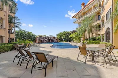 a patio with tables and chairs next to a swimming pool at SR9 Luxury Condo Across the Street from Beach in Tamarindo