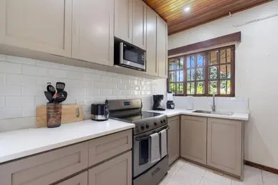 a kitchen with white cabinets and a stove top oven at VBM1 Beachside Cottage Steps from the Shore in Tamarindo