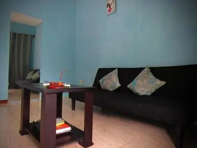 a living room with a black couch and a table at Rose House Manuel Antonio in Quepos