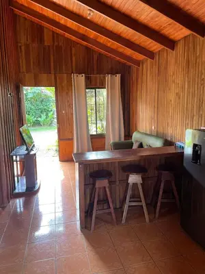 a kitchen with a bar with stools in a room at Cabinas La Catarata in Fortuna