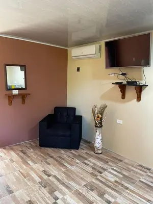 a living room with a black chair and a television at Cabinas La Catarata in Fortuna
