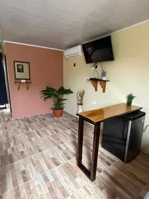 a living room with a table and a flat screen tv at Cabinas La Catarata in Fortuna