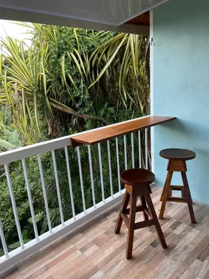 a wooden table and two stools on a balcony at Cabinas La Catarata in Fortuna