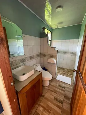 a bathroom with a sink and a toilet and a mirror at Cabinas La Catarata in Fortuna