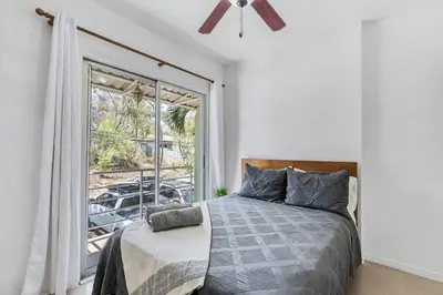 a bedroom with a bed and a large window at VVII2 2 bdrm with ensuite bathrms in centre of town in Tamarindo