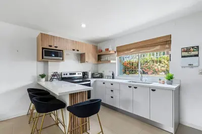a kitchen with white cabinets and black stools at VVII2 2 bdrm with ensuite bathrms in centre of town in Tamarindo