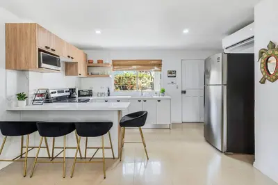 a kitchen with a stainless steel refrigerator and two bar stools at VVII2 2 bdrm with ensuite bathrms in centre of town in Tamarindo