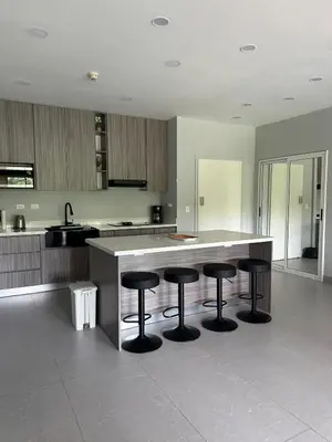 a kitchen with three bar stools and a counter at Casa blue in Jacó