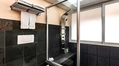 a bathroom with a shower with black tiles at Gaia Collection Hotels Manuel Antonio in Manuel Antonio