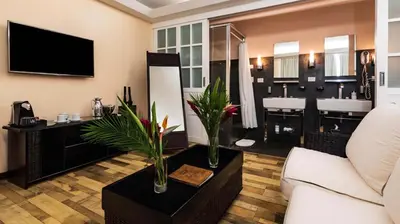 a living room with a white couch and a television at Gaia Collection Hotels Manuel Antonio in Manuel Antonio