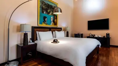 a bedroom with a large white bed and a flat screen tv at Gaia Collection Hotels Manuel Antonio in Manuel Antonio