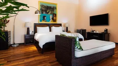 a hotel room with a bed and a chair at Gaia Collection Hotels Manuel Antonio in Manuel Antonio