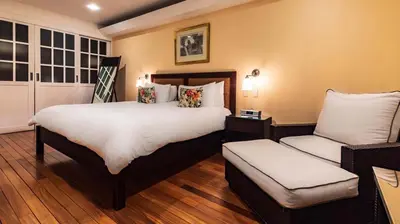 a bedroom with a large bed and a chair at Gaia Collection Hotels Manuel Antonio in Manuel Antonio