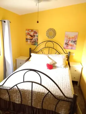 a bedroom with a bed with yellow walls at Happy Face House in Bogee