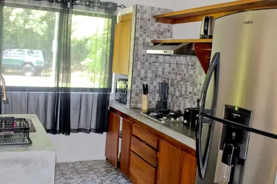 a kitchen with a stainless steel refrigerator and a window at Holly House La Fortuna in Agua Azul