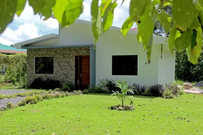 a house with a green lawn in front of it at Holly House La Fortuna in Agua Azul
