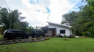 two trucks parked in front of a house at Holly House La Fortuna in Agua Azul