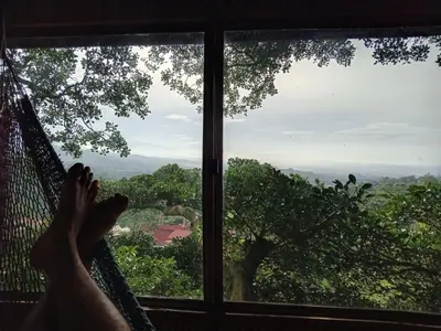 a person laying in a hammock looking out of a window at Casa del Arbol Feel Good in Naranjo