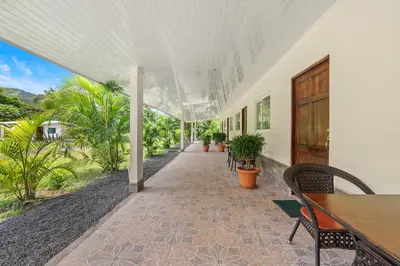 a porch with a table and chairs and a wooden door at Finca Brisas de la Montaña in Coco