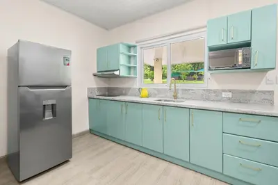 a kitchen with blue cabinets and a refrigerator at Finca Brisas de la Montaña in Coco