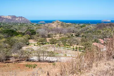 a view of a field with the ocean in the background at Finca Brisas de la Montaña in Coco