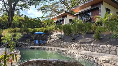 a house with a pond in front of it at Fully furnished lodge with hot tub and pool - Alto Castillo in San José
