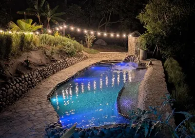 a swimming pool with lights in a yard at night at Fully furnished lodge with hot tub and pool - Alto Castillo in San José