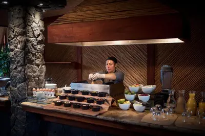 a woman standing behind a counter with a bunch of cupcakes at Peace Lodge in Vara Blanca