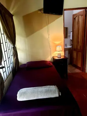 a bedroom with a bed and a window at Arenal Hostel La Catarata in Fortuna