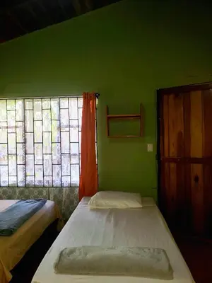 a small room with two beds and a window at Arenal Hostel La Catarata in Fortuna