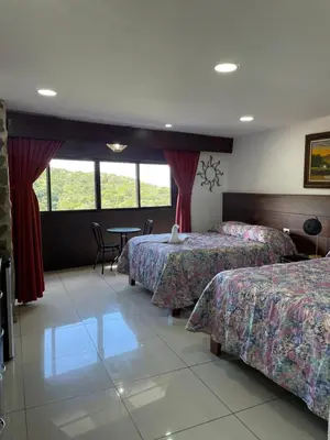 a hotel room with three beds and a table at Cabinas Vista Al Golfo in Monteverde Costa Rica