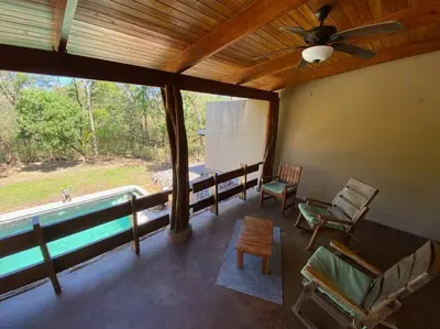 a living room with a pool and a ceiling fan at Jim's Beach House in Playa Grande
