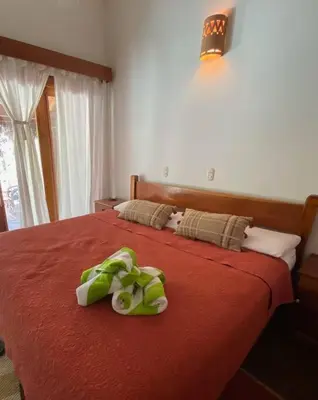 a green stuffed animal laying on a red bed at Jim's Beach House in Playa Grande