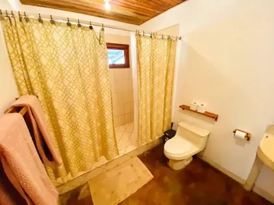 a bathroom with a shower curtain and a toilet at Jim's Beach House in Playa Grande