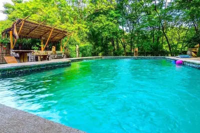 a swimming pool with blue water in a yard at Jim's Beach House in Playa Grande