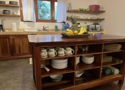 a kitchen counter with a island with a bowl of fruit at Jim's Beach House in Playa Grande