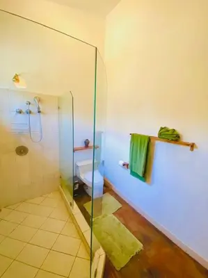 a bathroom with a glass shower and a toilet at Jim's Beach House in Playa Grande