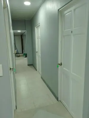 an empty hallway with two white doors and a tile floor at Hospedaje Casa Académica in San Pedro