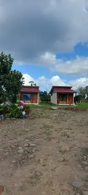 two small buildings in a field with a yard at Cabinas Río celeste in Upala