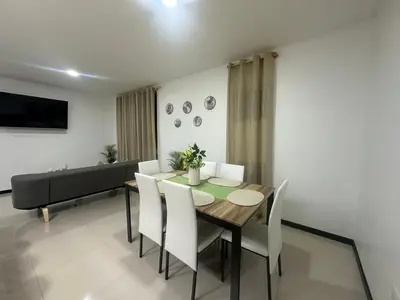a dining room with a table and chairs and a couch at Condo Apt 3BR,2BA, 4mi from SJO Airport, Pool,Gated, Gym in Desamparados