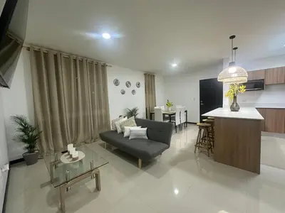 a living room with a couch and a kitchen at Condo Apt 3BR,2BA, 4mi from SJO Airport, Pool,Gated, Gym in Desamparados