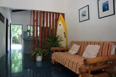a living room with a couch and a surfboard on the wall at Tropical Camas Surf House in Pochotal