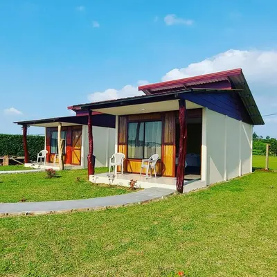 a small house with a porch and two chairs at Cabinas Río Celeste in Upala