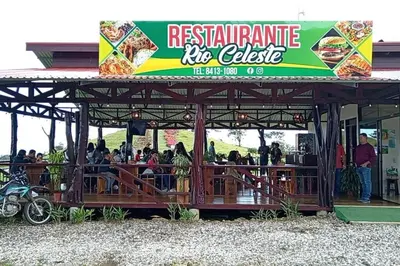 a restaurant rideicle with people sitting on a deck at Cabinas Río Celeste in Upala