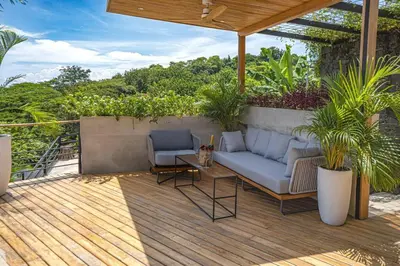 a patio with a couch and chairs on a wooden deck at Blanko Mar Ocean view in Santa Teresa Beach