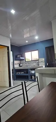 a room with a table and a kitchen with blue walls at Villas Atardecer Tamarindo in Santa Rosa
