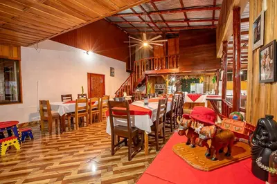 a dining room with a table and chairs and a dining room with wooden floors at Arenal Family Home - Families & Friends Gateway in Fortuna